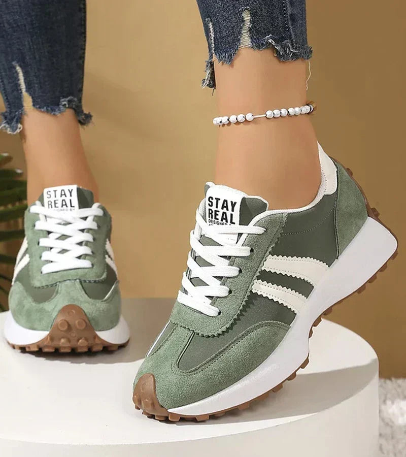 Green panelled women's sneakers with white laces and striped sides