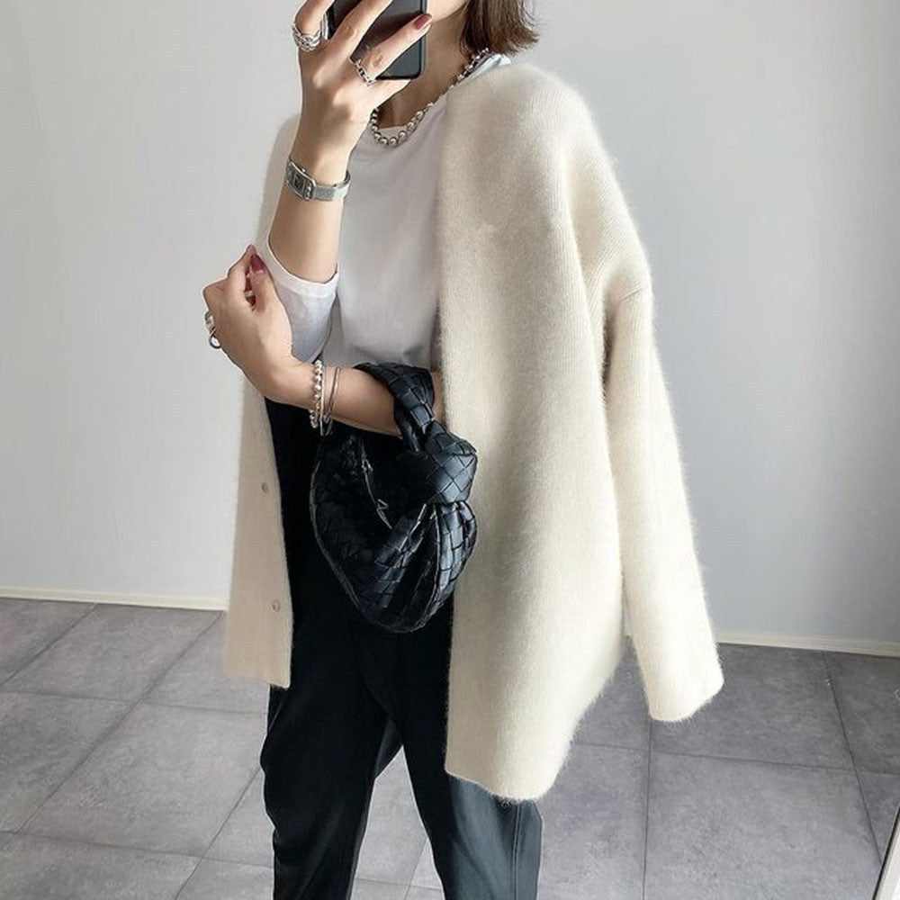 Woman wearing a fuzzy knit collarless longline cardigan with snap buttons and side pockets