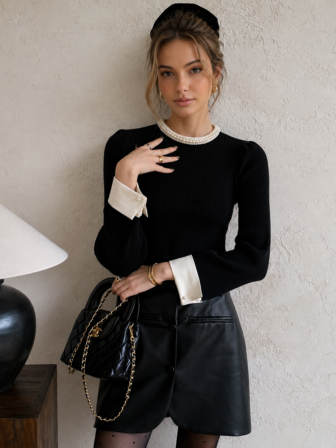 Women's black ribbed knit top with pearl-trimmed round collar and white contrast cuffs
