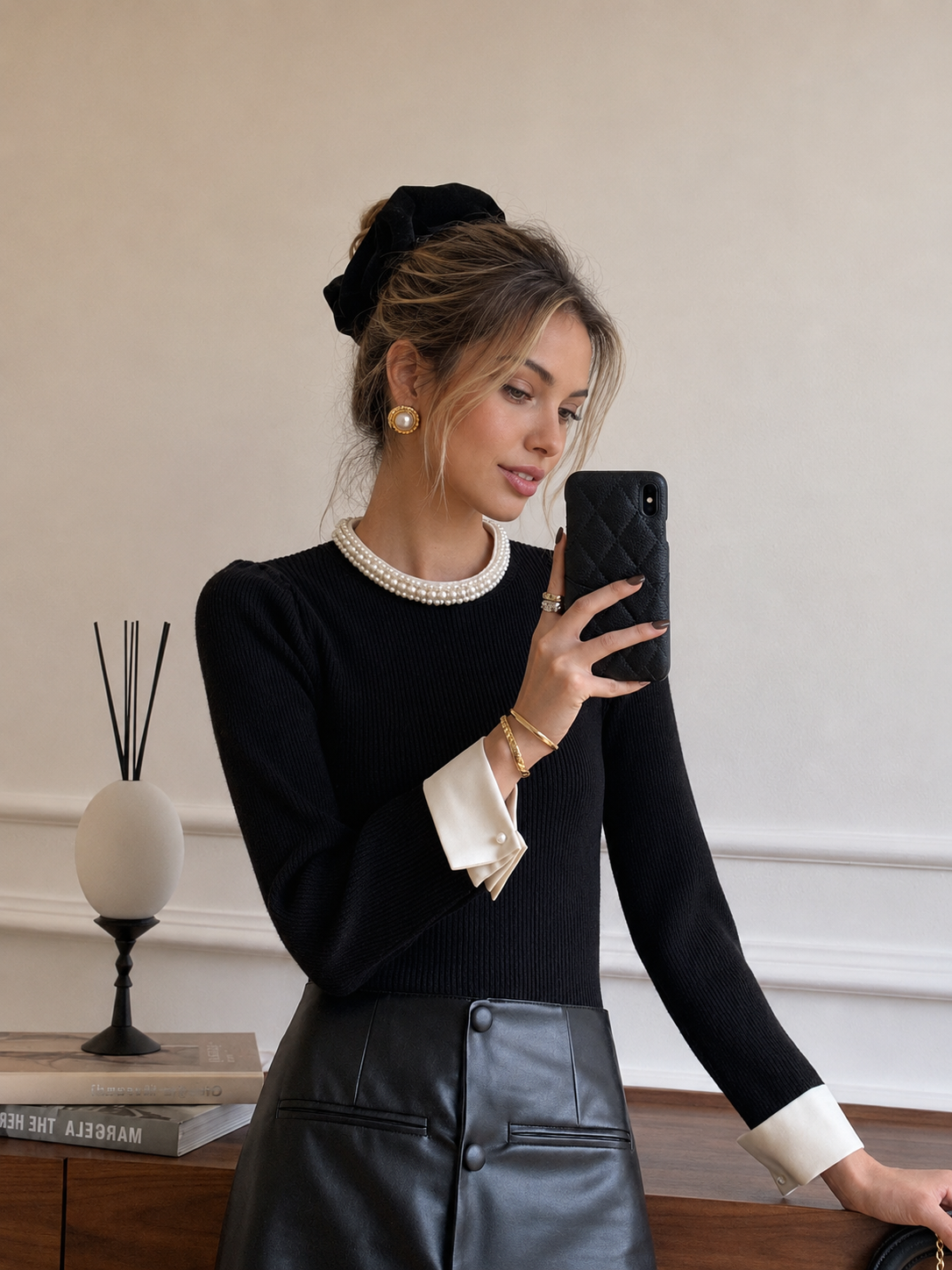 Women's black ribbed knit top with pearl-trimmed round collar and white contrast cuffs